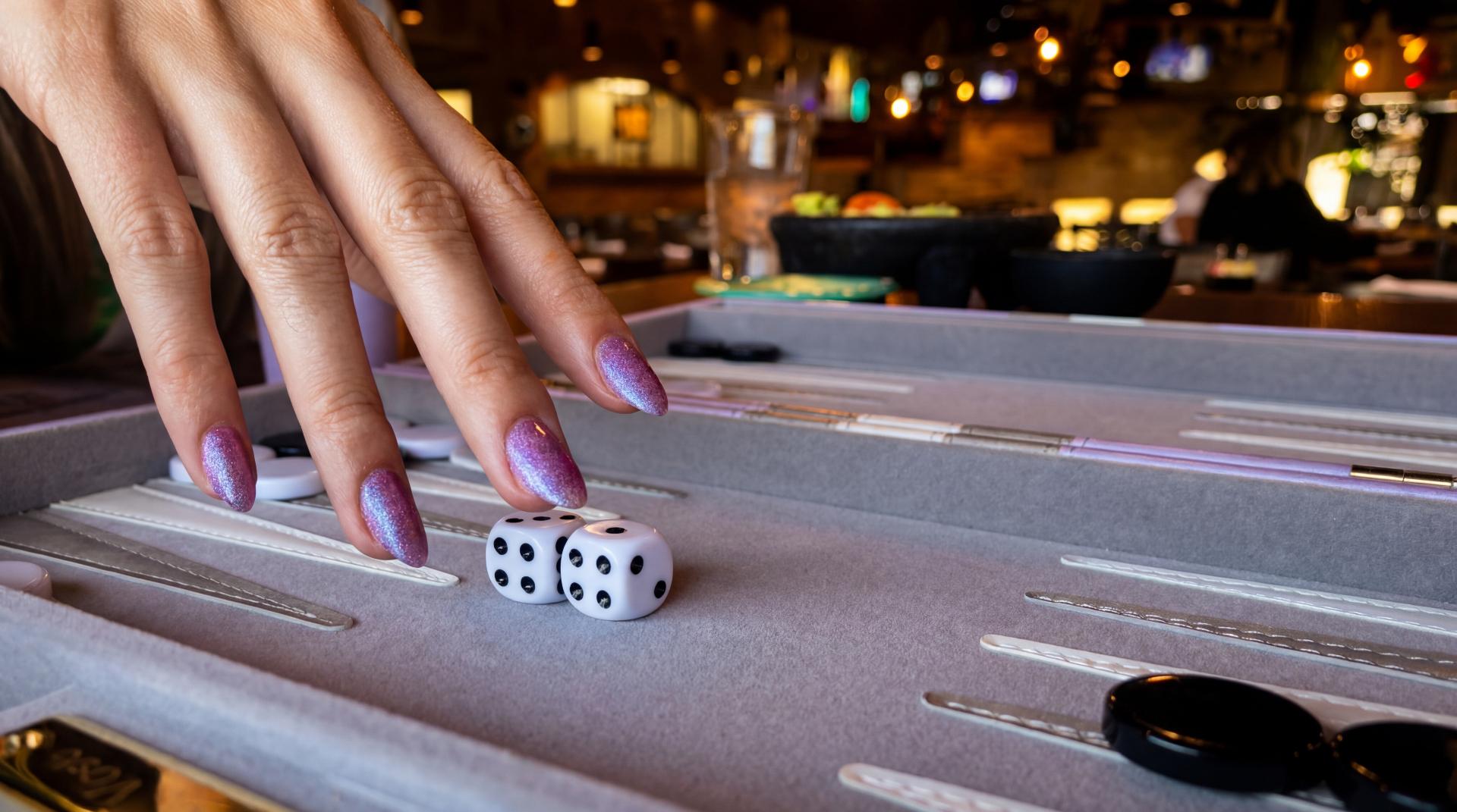 Hand rolling dice on a backgammon board